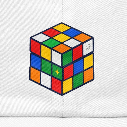 A white baseball cap featuring a colorful 3D Rubik's cube graphic printed on the front, set against a plain white background.